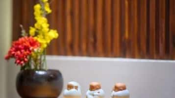 Una bandeja de madera con tres figuritas pequeñas y un florero con flores.