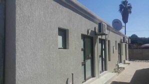 A building with a textured facade, multiple windows, and a satellite dish. - Tsumeb Guesthouse Kamho (Tsumeb)