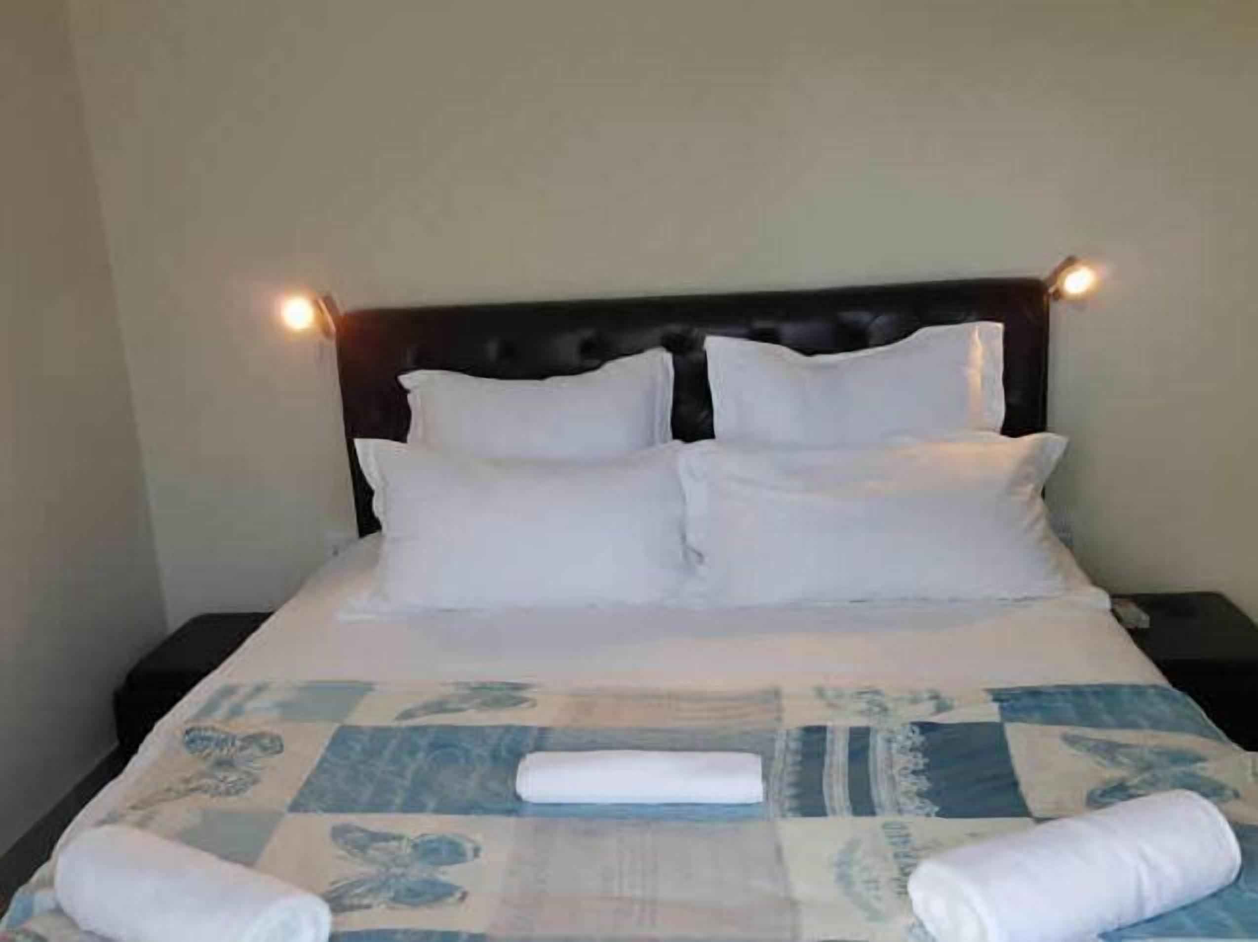 A neatly made bed with white linens and a blue patterned bedspread.