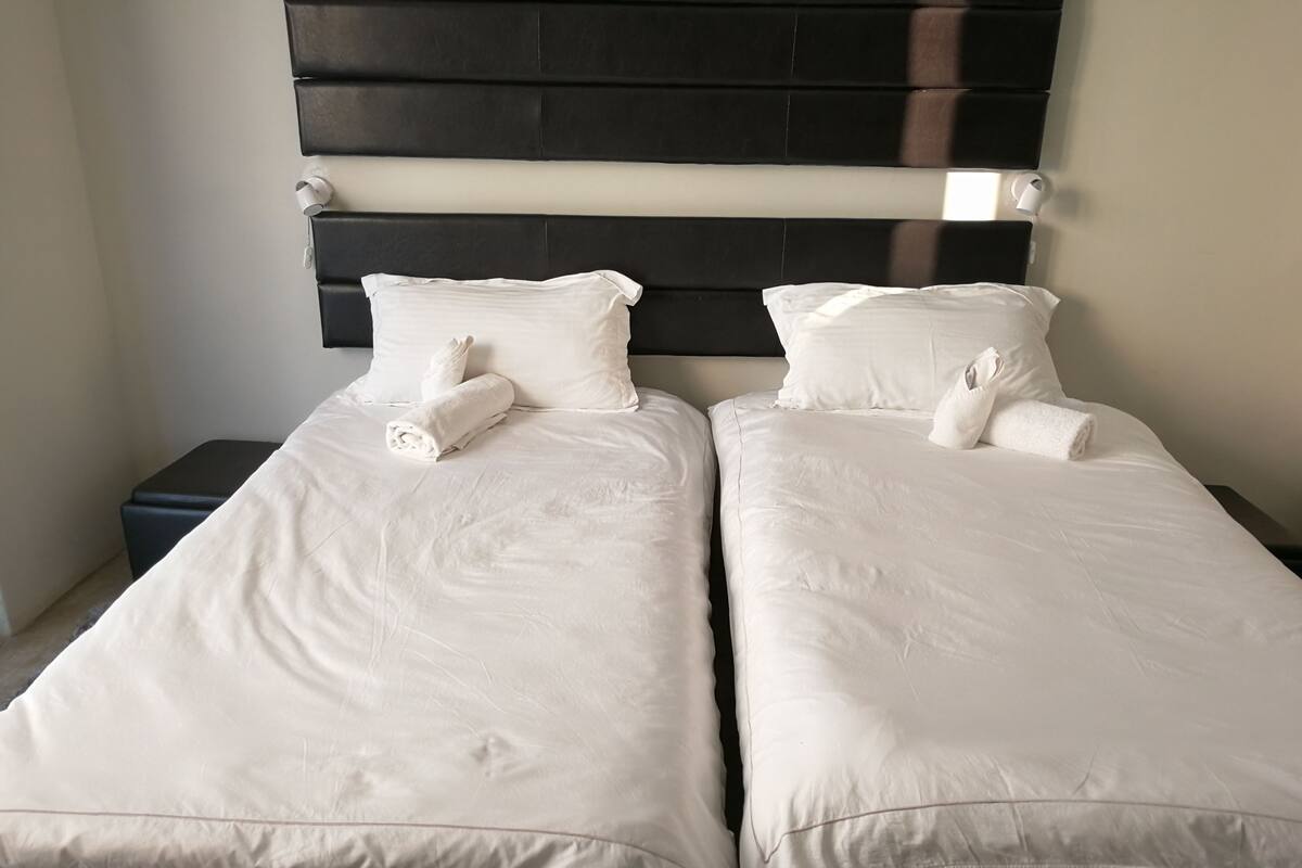 A double bed with white bedding and pillows, a dark headboard, and a small bedside table.
