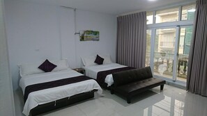 Ein Hotelzimmer mit zwei Betten, einer Bank, einem Fenster mit Vorhängen und einem Bild an der Wand.
