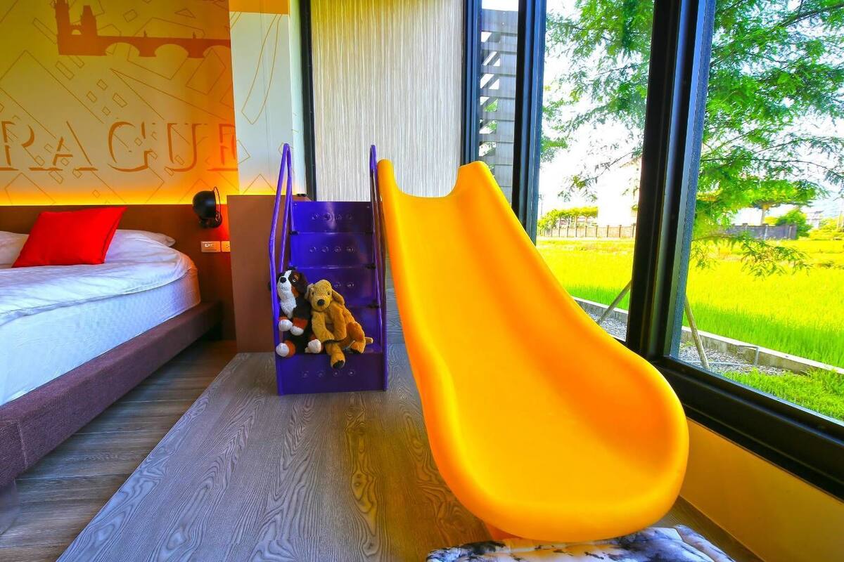 A room with a bed, a purple slide, and a yellow slide.