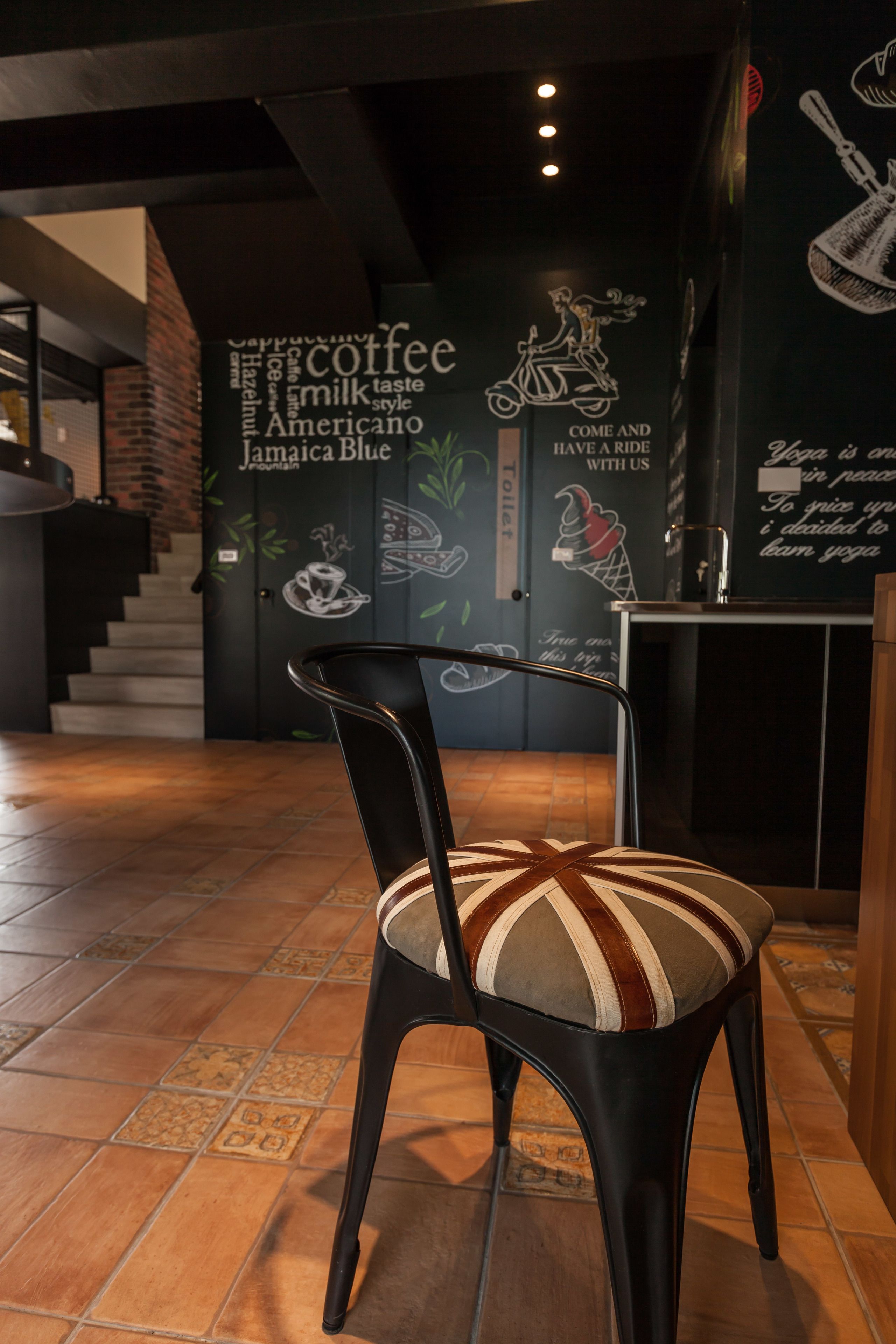 A chair with a striped cushion in a cafe with a mural on the wall.