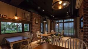 A restaurant with brick walls, large windows, and wooden tables and chairs. - More Manor (Dongshan)
