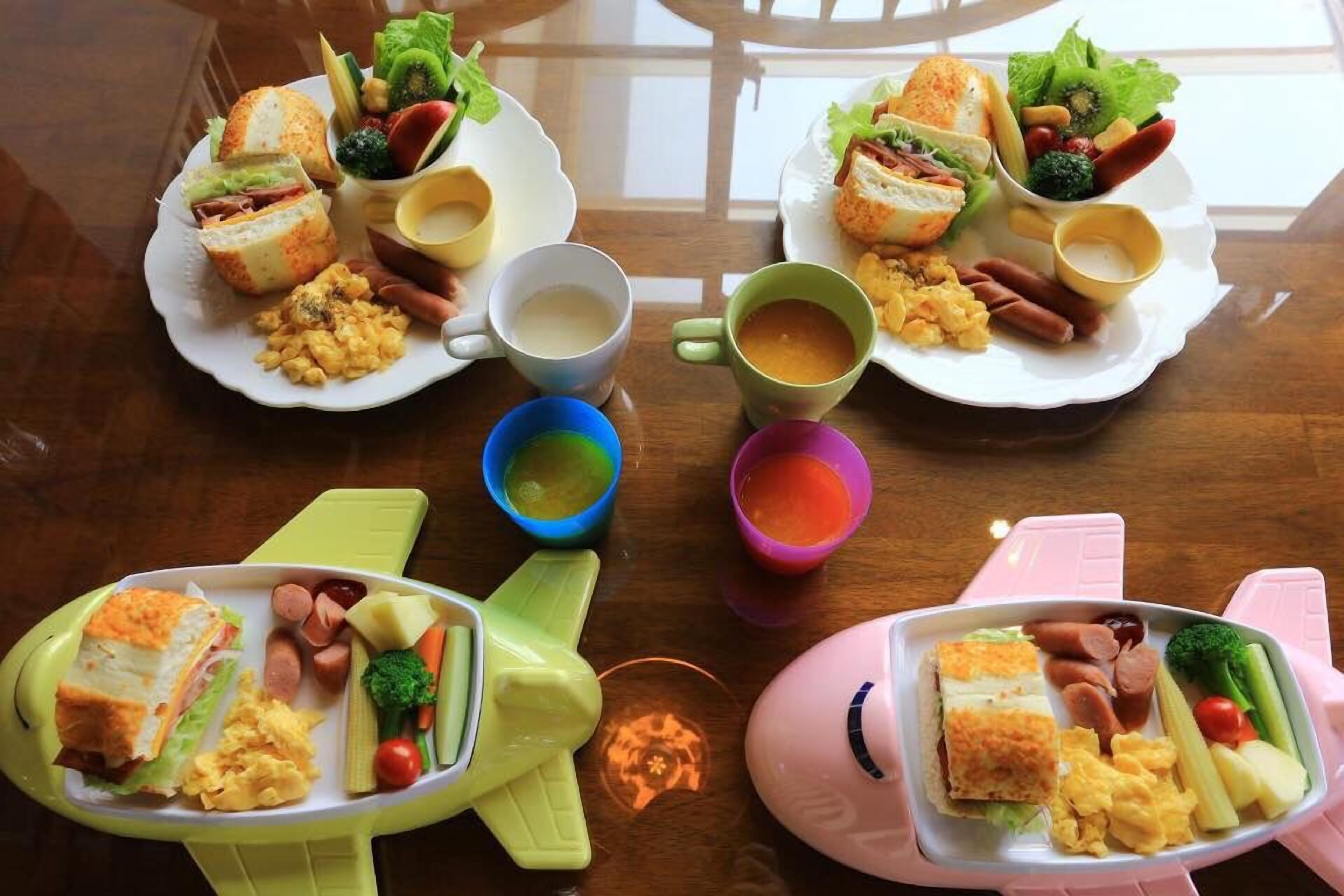 A table with four plates of food, each containing sandwiches, vegetables, and condiments.