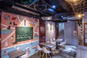 Un dormitorio acogedor de hostal con un mural, una pizarra y una escalera que lleva a otra zona.