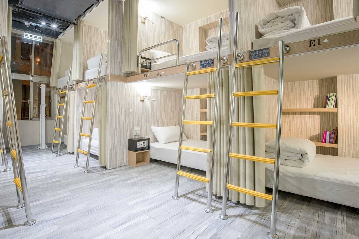 Ein Hotelzimmer mit Etagenbetten, einem Schreibtisch, einem Stuhl, einem Nachttisch und einem Bücherregal.