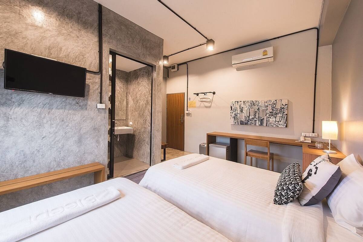 Ein modernes Hotelzimmer mit einem großen Bett, einem Schreibtisch, einer Dusche und einem an der Wand befestigten Fernseher.
