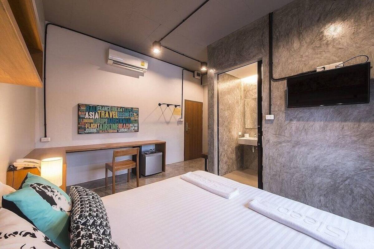 Ein modernes Hotelzimmer mit Bett, Schreibtisch, Stuhl, Fernseher und Klimaanlage.
