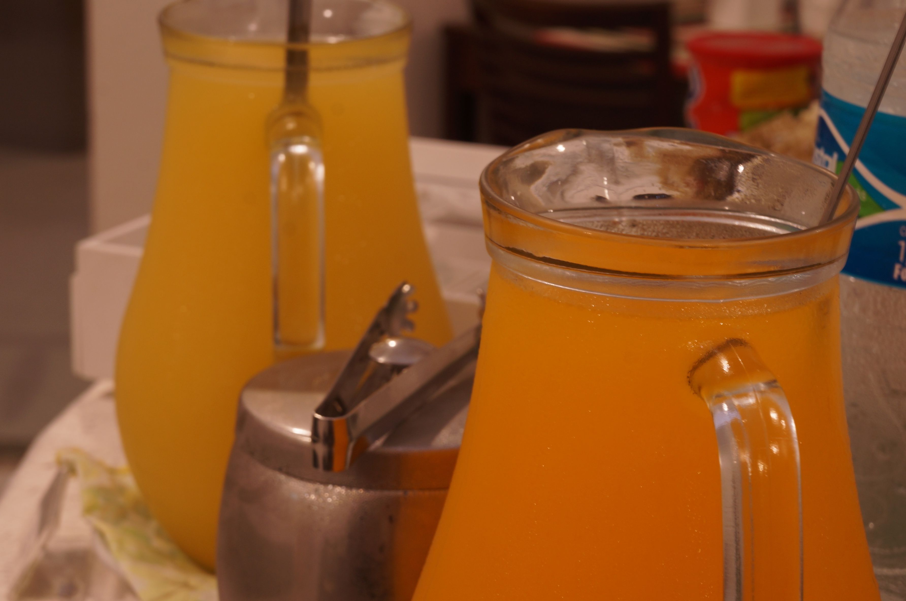 Dos dispensadores de vidrio llenos de jugo de naranja.