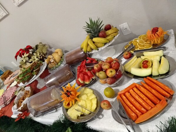 Une table de buffet proposant une variété d’aliments, notamment des fruits, des légumes et des sandwichs.