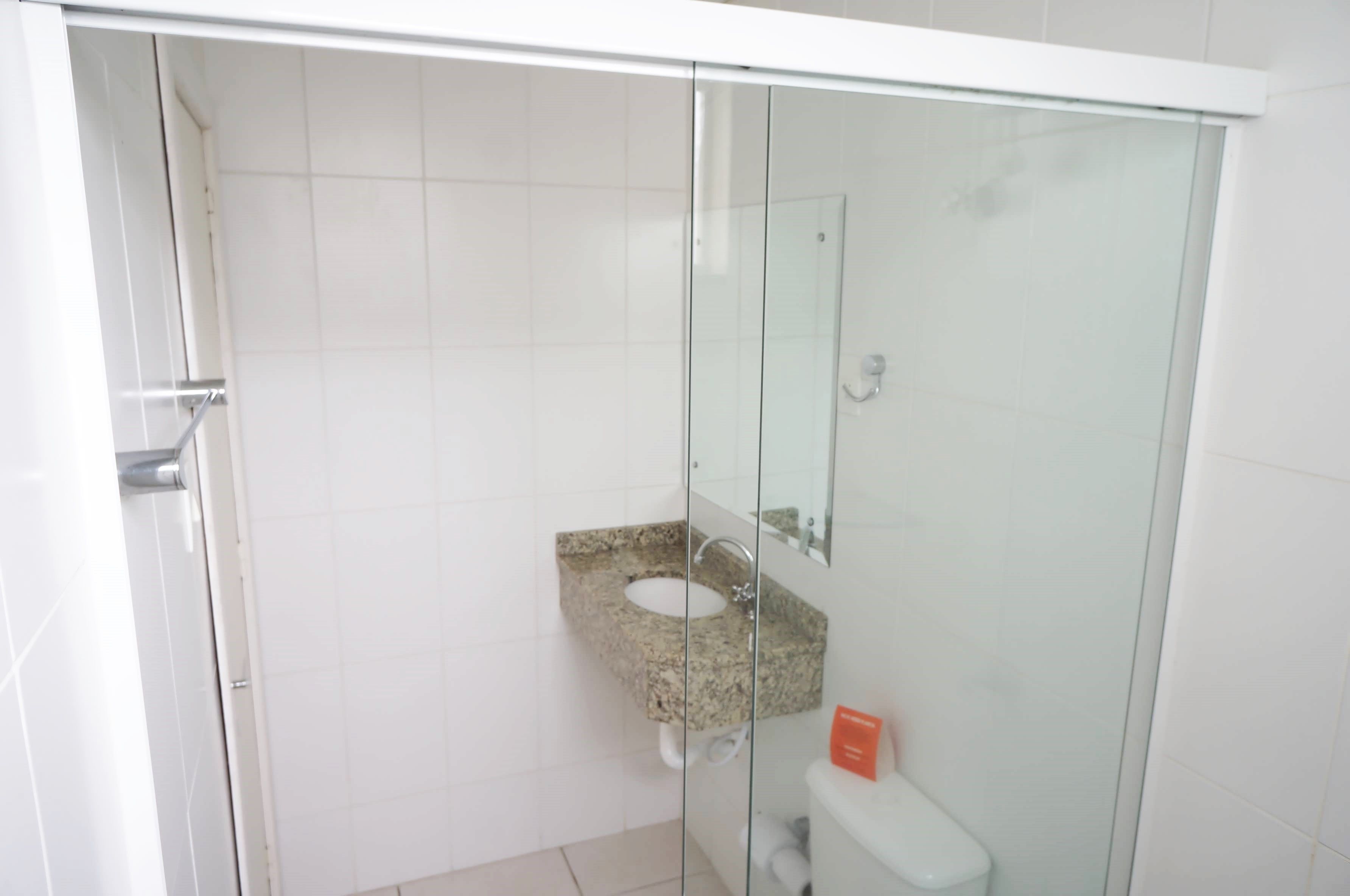 A bathroom with a glass-enclosed shower, a granite sink, and a white toilet.