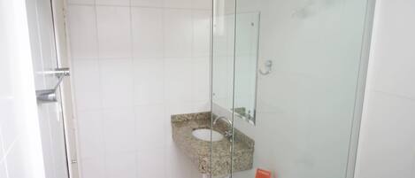 A bathroom with a glass-enclosed shower, a granite sink, and a white toilet.