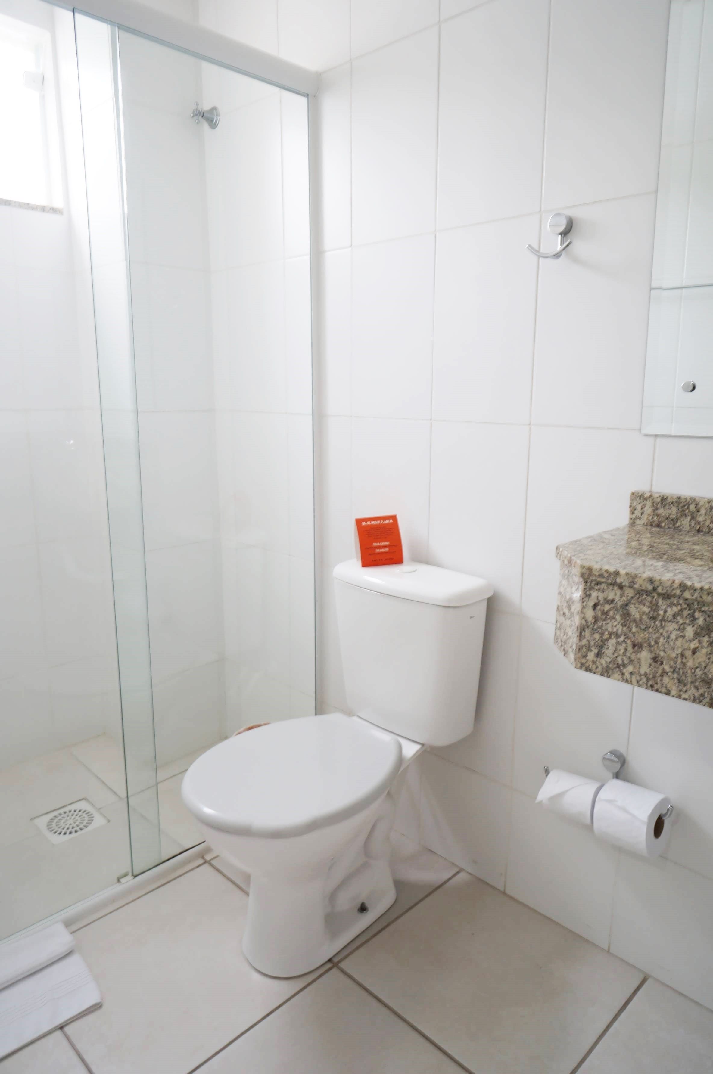 A bathroom with a glass shower enclosure, a white toilet, and a marble countertop.