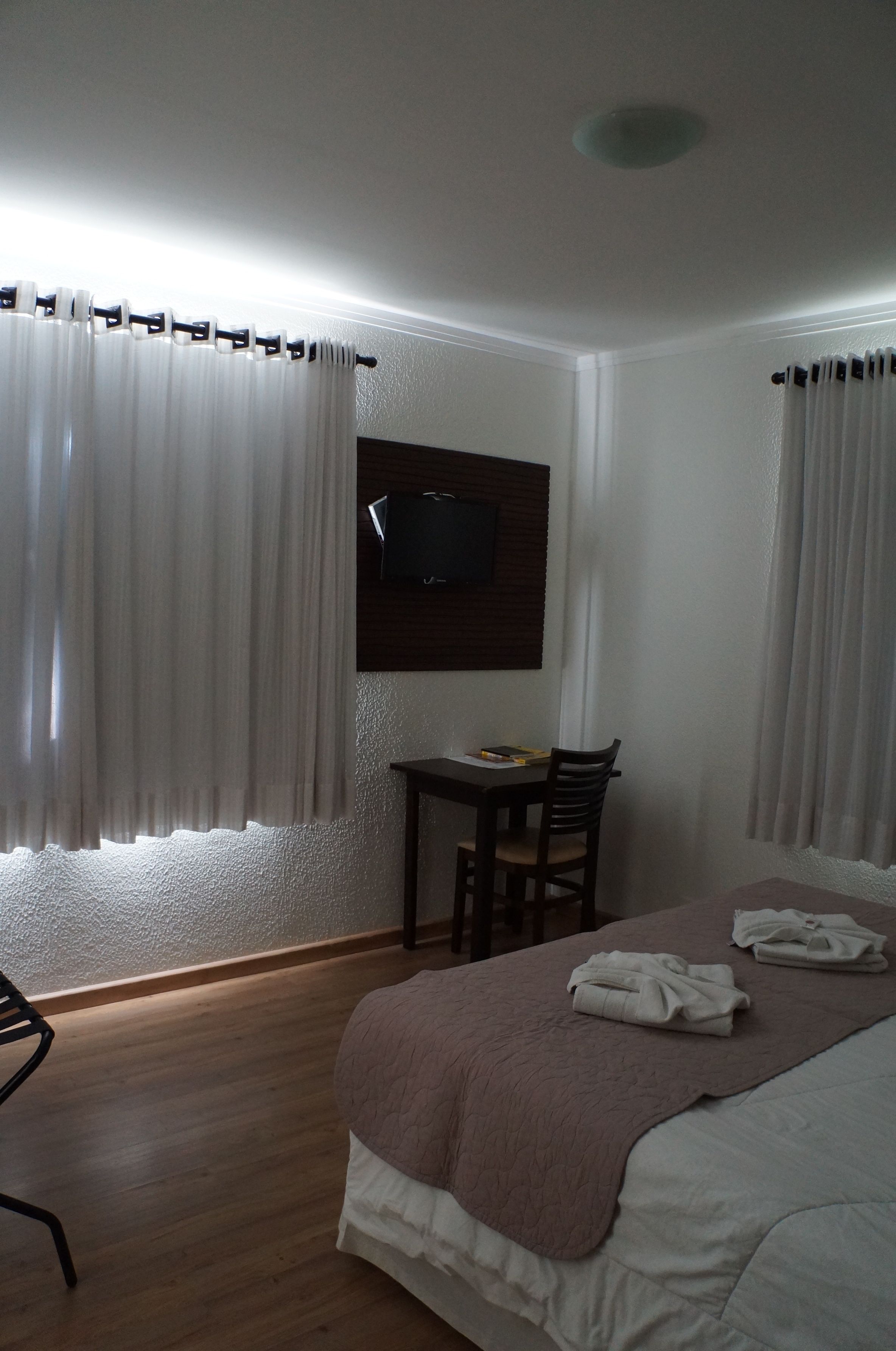A hotel room with a bed, a desk, and a chair.