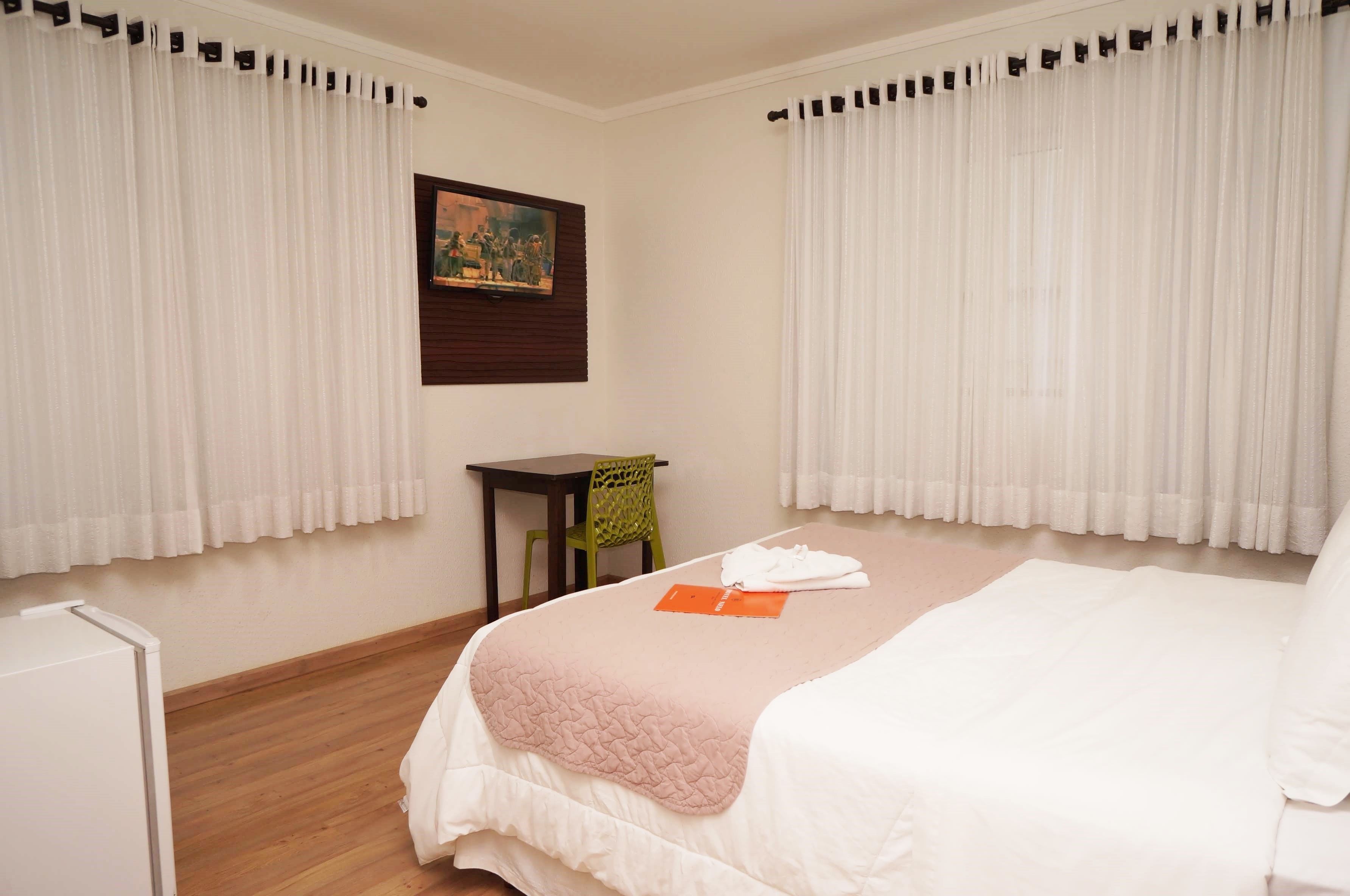 Habitación de hotel con cama, una mesita, una silla y un cuadro en la pared.