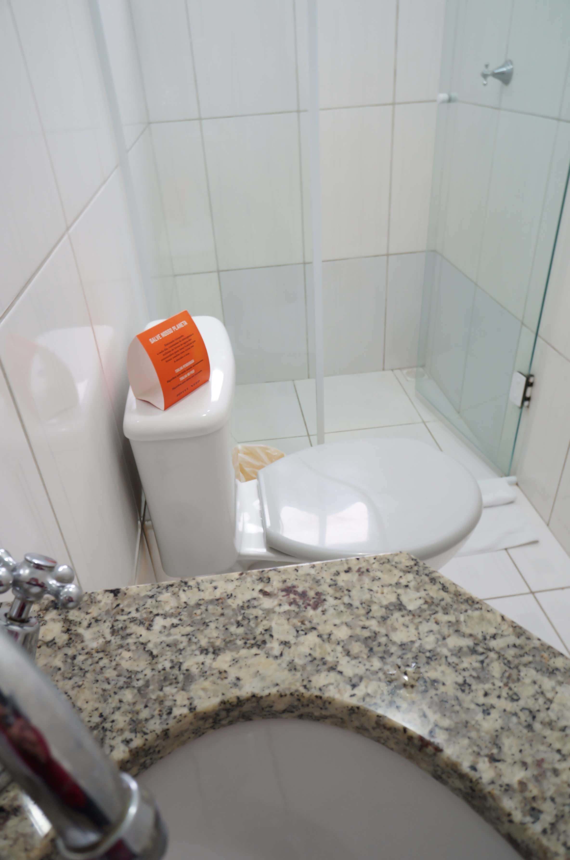Un baño con inodoro blanco, lavamanos de granito y cabina de ducha de vidrio.