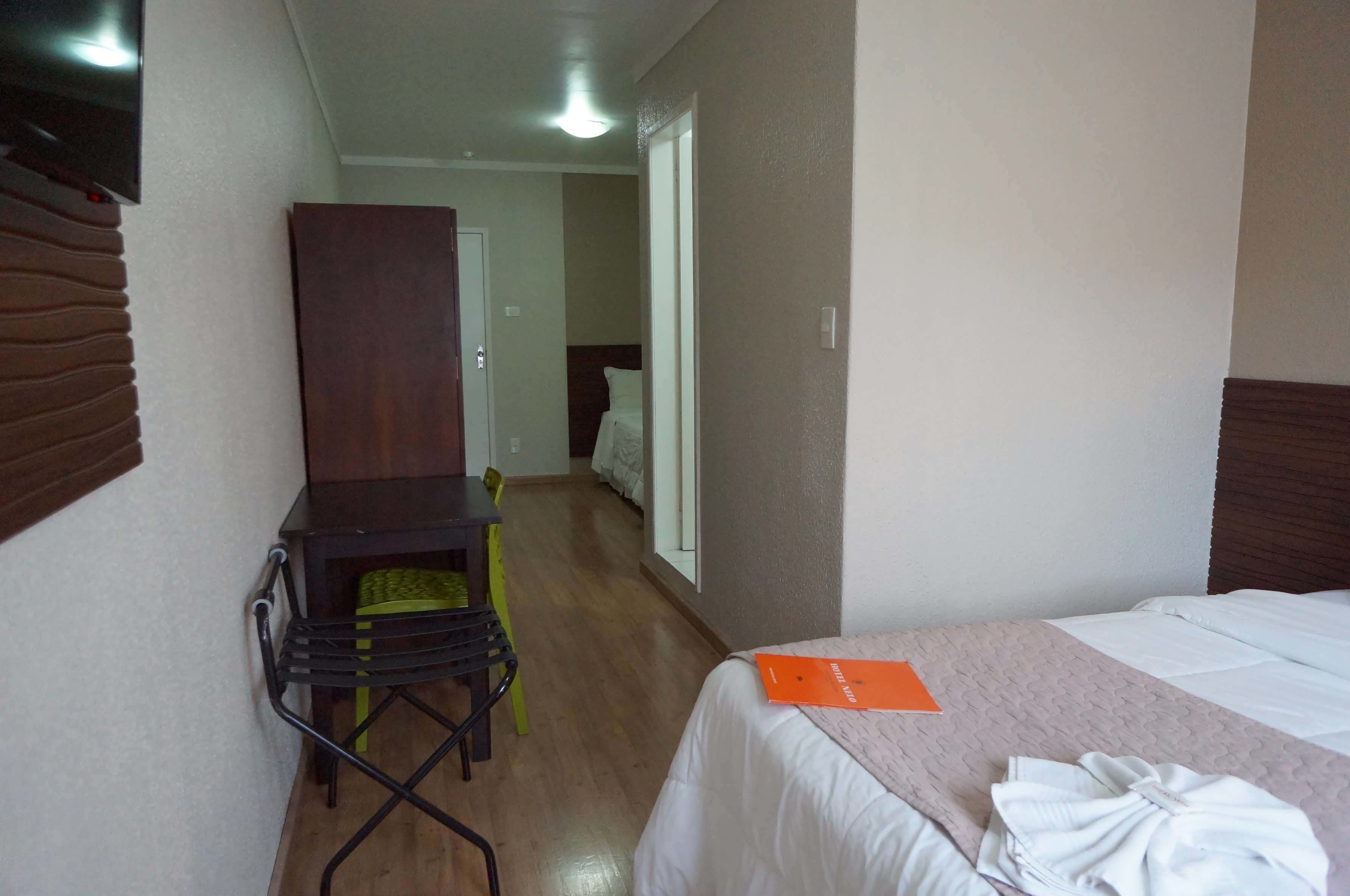 Una habitación de hotel con una cama, un escritorio, una silla y un armario.