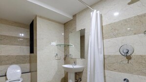 A bathroom with a toilet, sink, and shower area. - Galaxy Inn (Kolhapur)