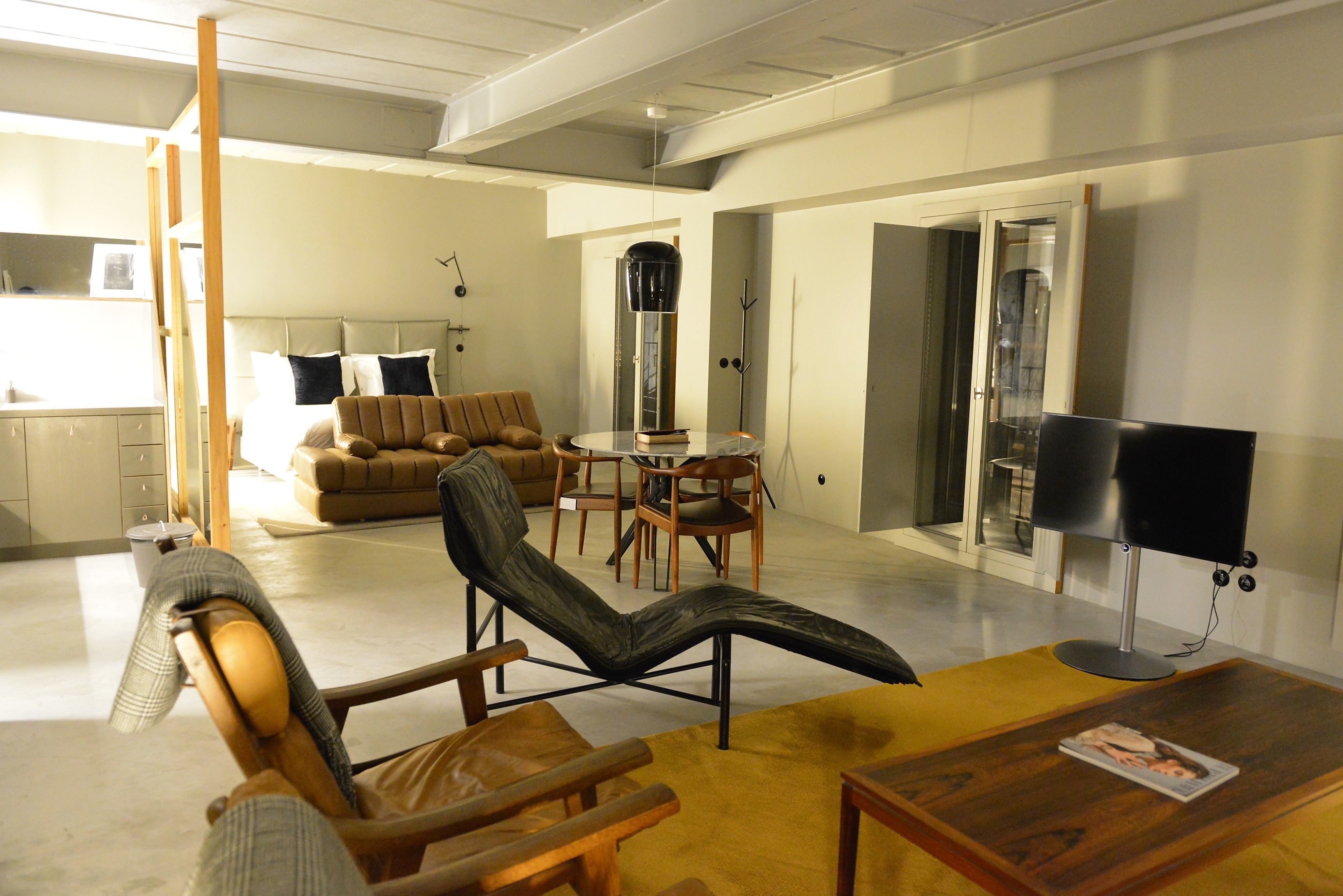 Un salon moderne comprenant un canapé, un fauteuil, une table basse et un téléviseur.