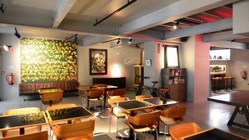 Ein modernes Interieur mit Tischen, Stühlen, einem großen Wandbild und einer Bar.