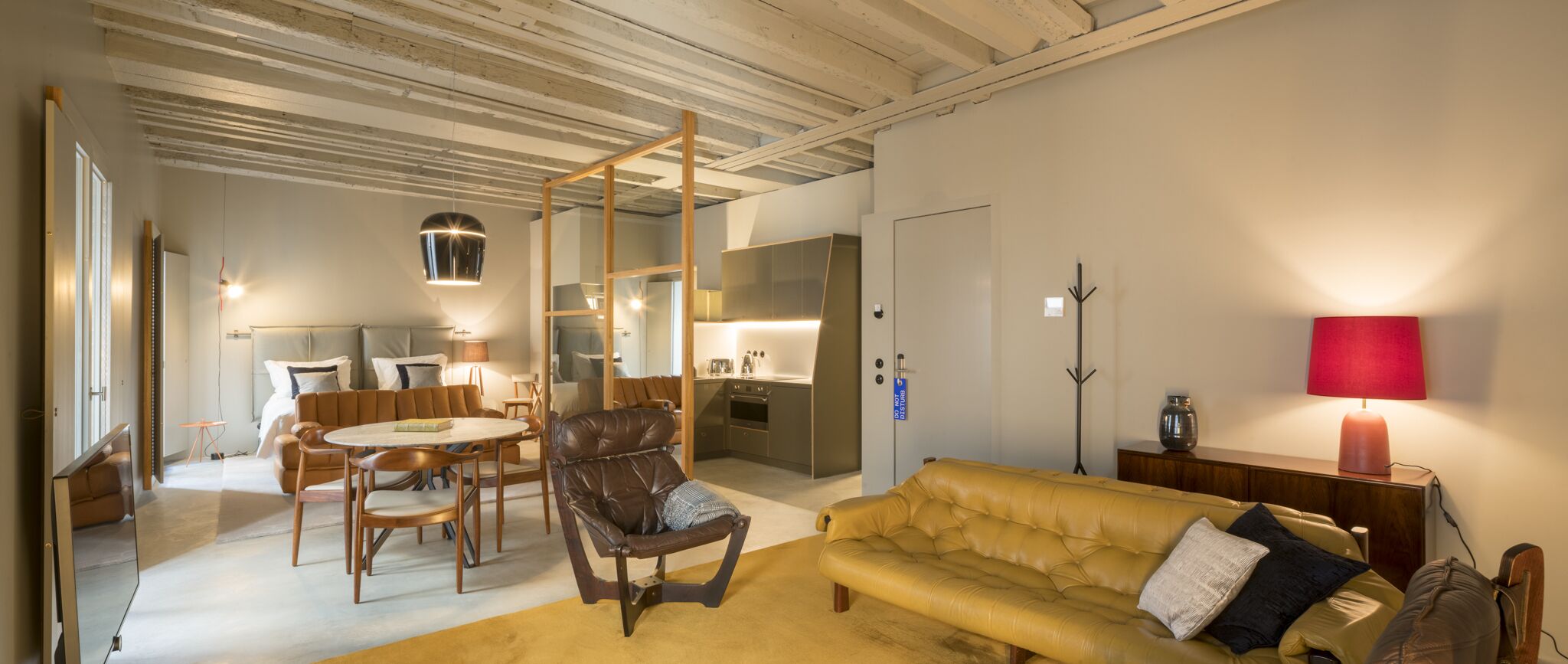 Una sala de estar moderna con sofá, sillas, una mesa de comedor y una zona de cocina.