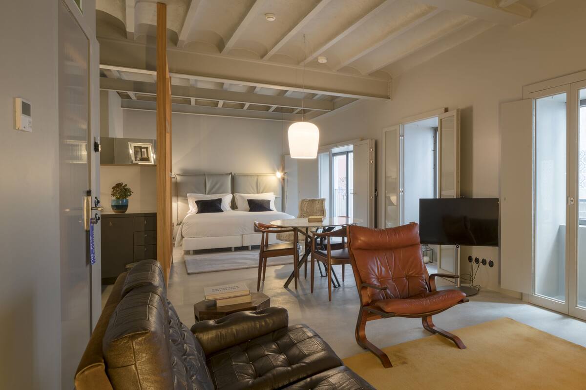 Un salon moderne comprenant un canapé, un fauteuil en cuir, un coin repas et un téléviseur.