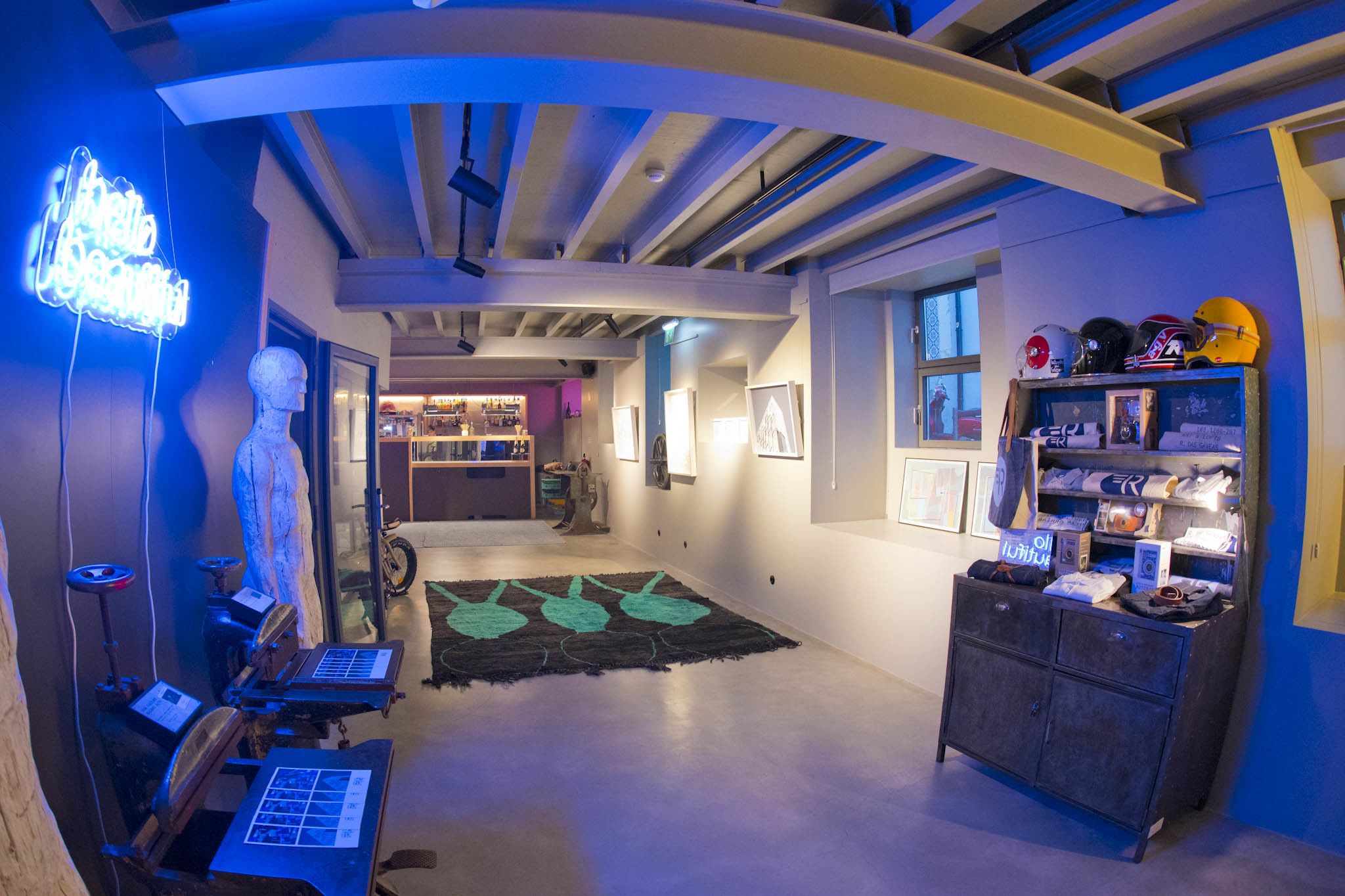 Un interior moderno con un letrero de neón, un maniquí, una bicicleta y una exhibición de cascos.