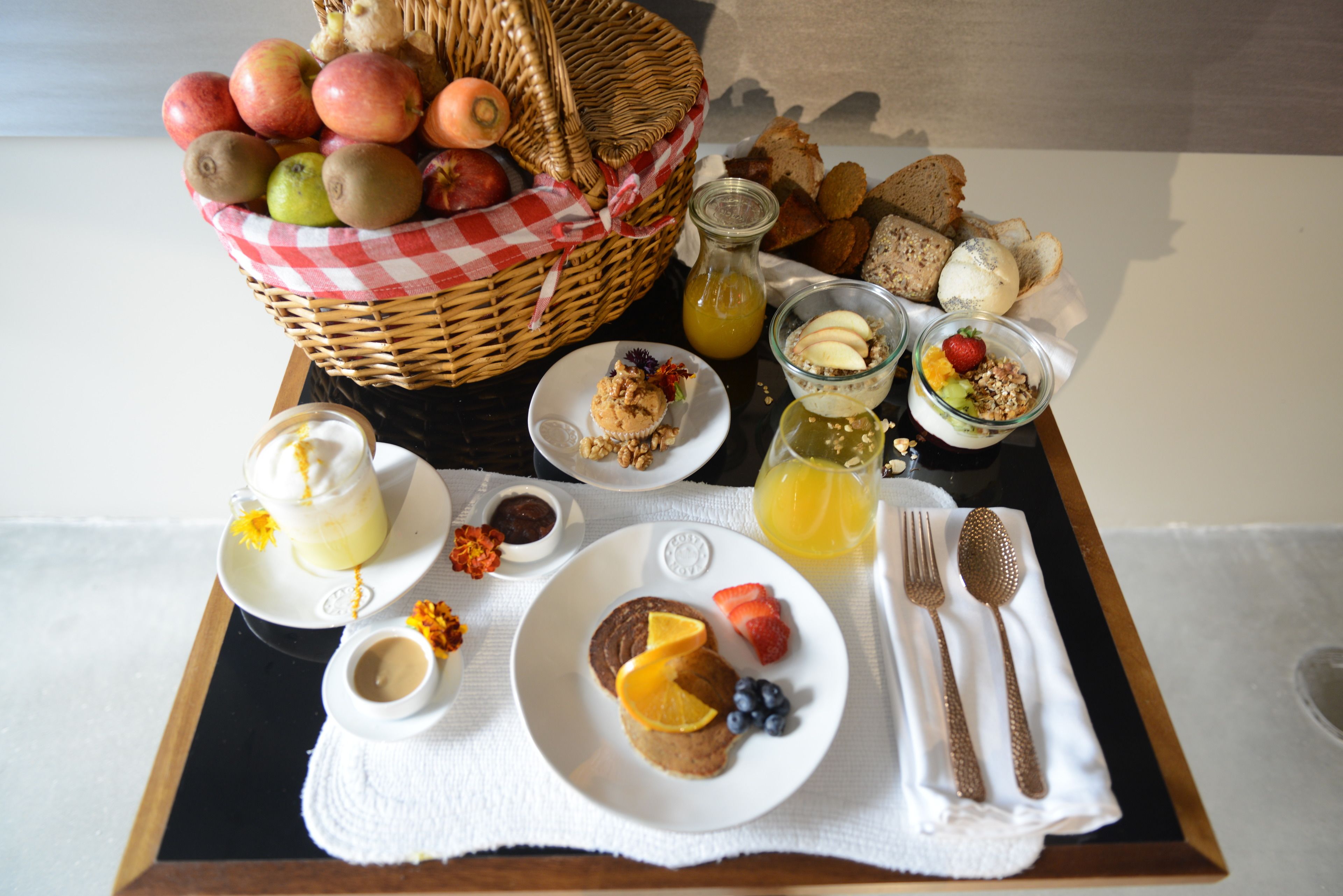 A breakfast tray with various food items including fruits, bread, and beverages.