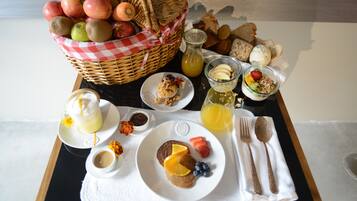 A breakfast tray with various food items including fruits, bread, and beverages.