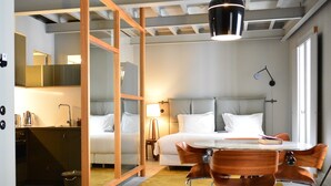 Une chambre d’hôtel comprenant un lit, une table de chevet, une lampe et un coin repas avec des chaises et une table.