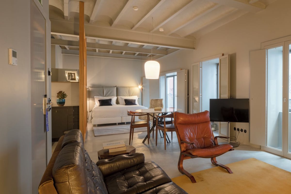 Ein modernes Wohnzimmer mit einer Couch, einem Sessel, einem Fernseher, einer roten Lampe und einem Holzschrank.