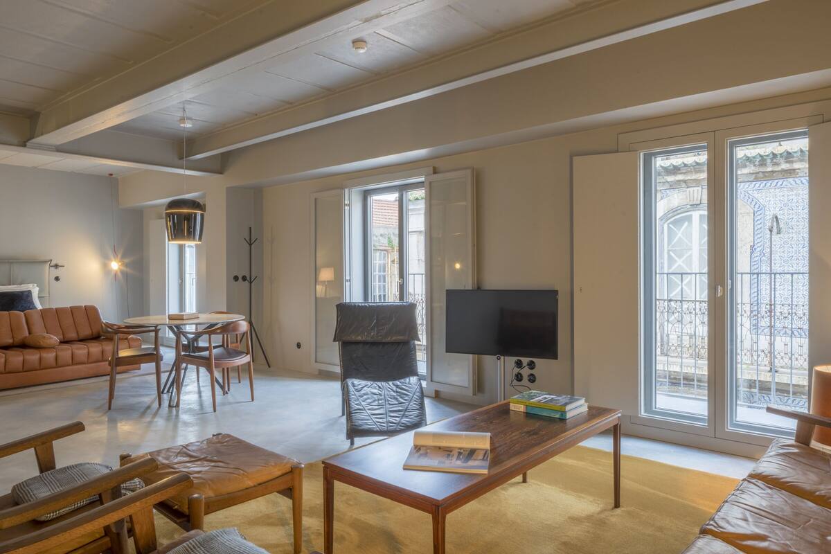 Un salon spacieux avec un canapé, une table basse et un téléviseur. Il y a un balcon avec vue.