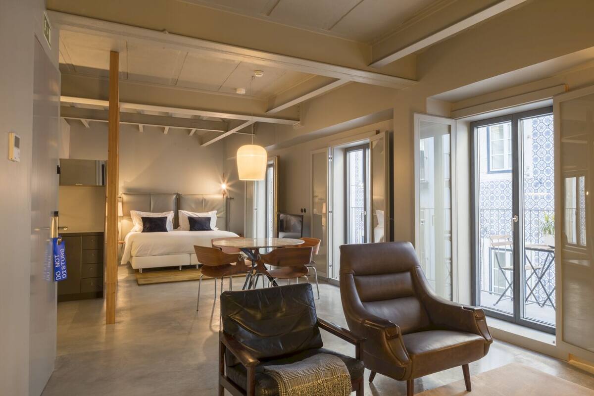 Une chambre d’hôtel spacieuse comprenant un lit, un coin repas, un fauteuil et un balcon avec vue.