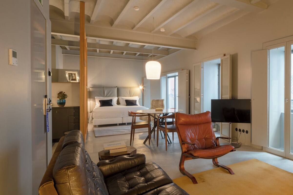 Un salon moderne avec un canapé, un fauteuil, un téléviseur, une lampe rouge et un meuble en bois.