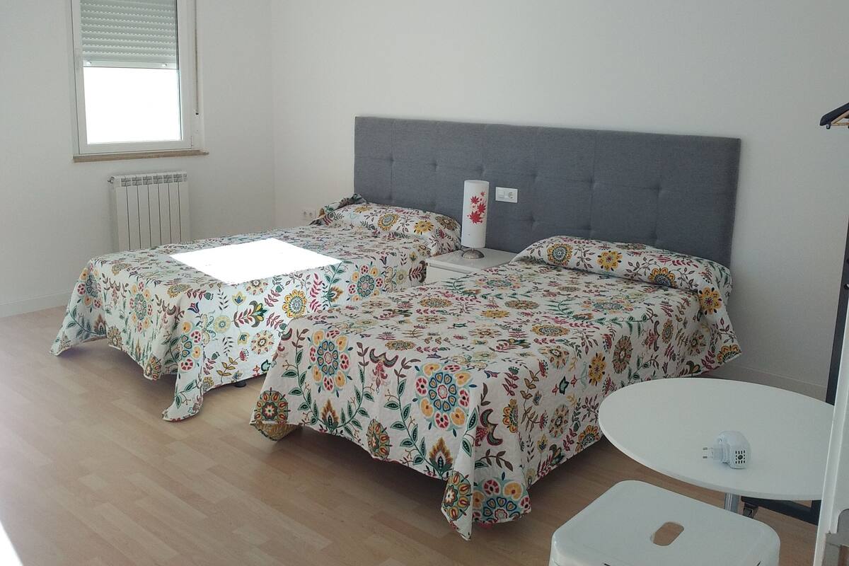 A room with two beds, a small round table, and a radiator.