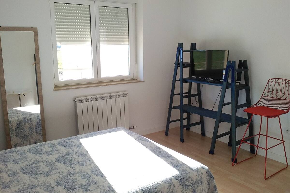 A room with a bed, a desk with a computer, a chair, and a radiator.