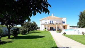 Ein zweigeschossiges Haus mit Balkon, Schwimmbad und gepflegtem Rasen.