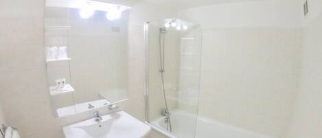 A bathroom with a sink, mirror, and a glass-enclosed shower area.