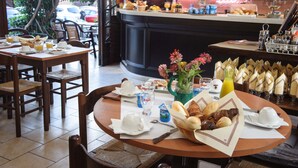 Een ontbijtinrichting met tafels, stoelen en een bar, met diverse dranken en gebak.