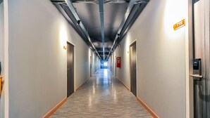 Un lungo corridoio ben illuminato con pavimento in legno, porte su entrambi i lati e una targa che indica la stanza numero 716.
