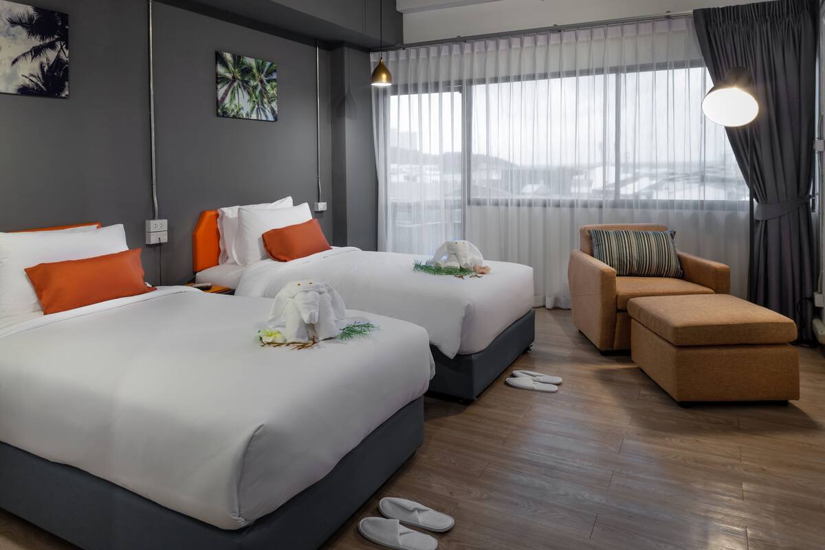 A hotel room with two beds, a sofa, and a view of the city.