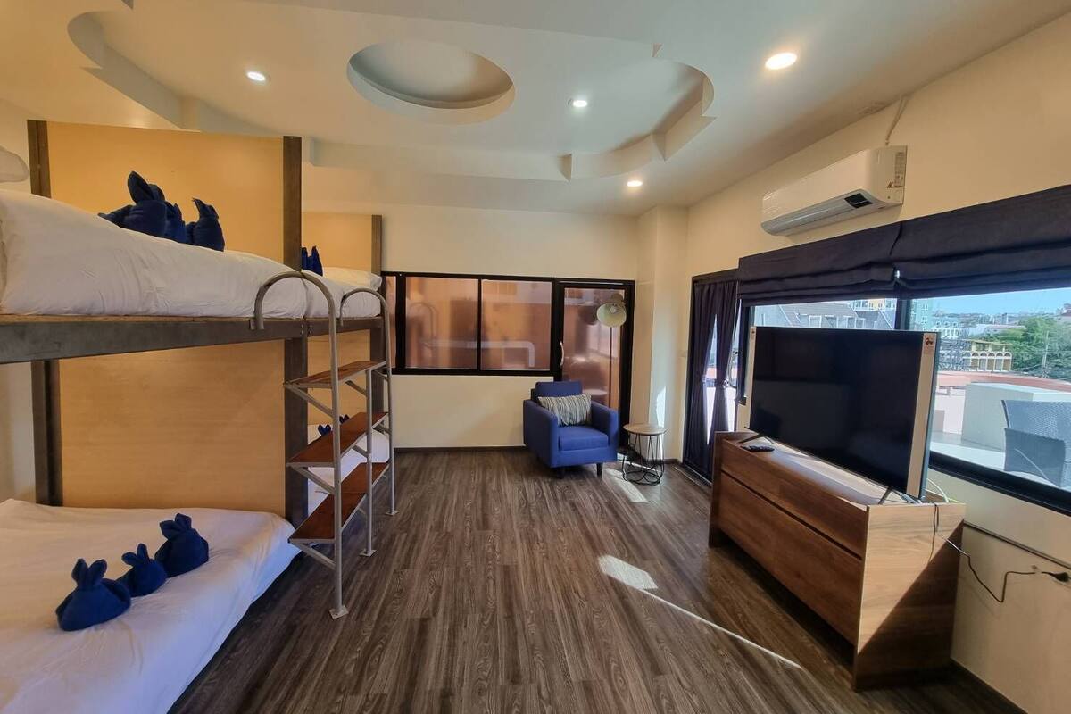 A hotel room with bunk beds, a TV, a desk, and a window with a city view.