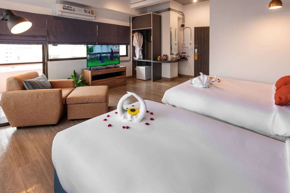 A modern hotel room with a sofa, a bed, a TV, and a minibar.