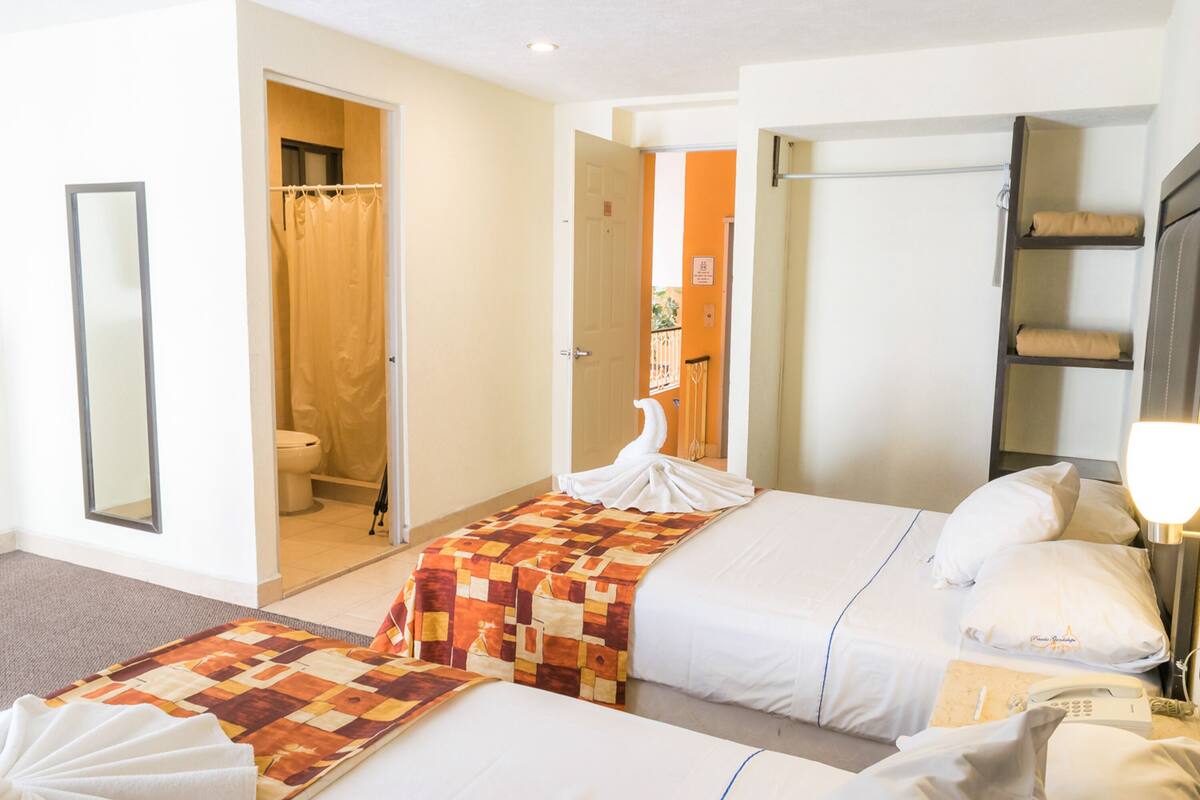 A hotel room with two beds, a bathroom, and a wardrobe.