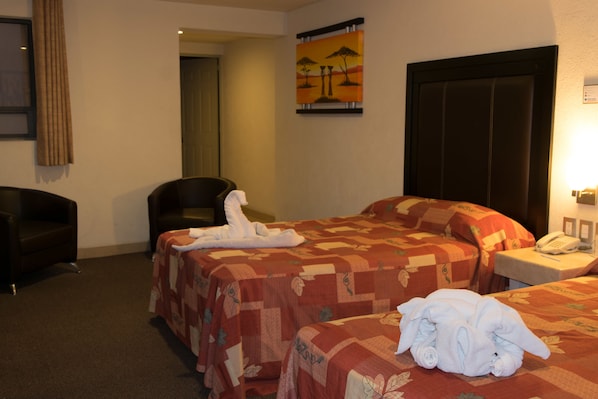 A hotel room with two beds, a chair, a desk with a phone, and a painting on the wall. - Posada Guadalupe (Puebla)