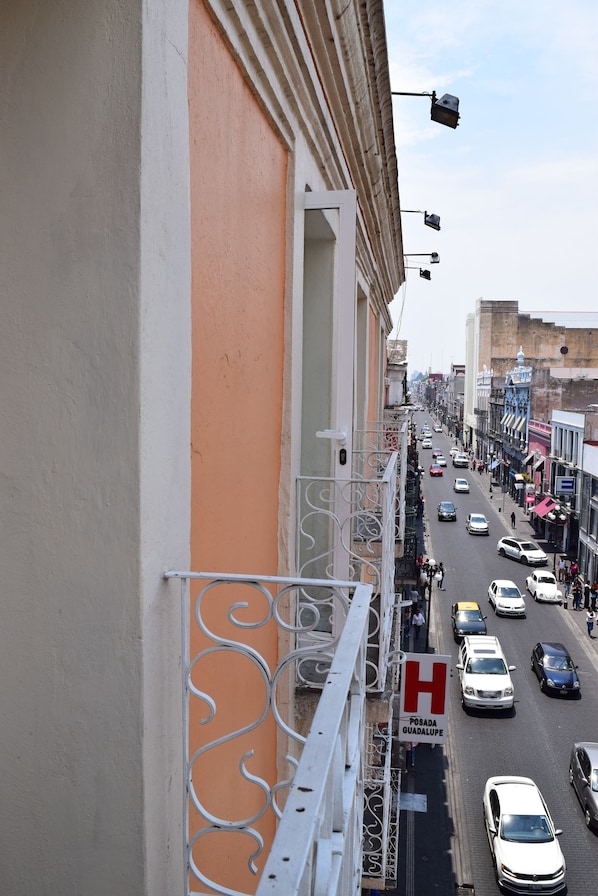 A street view with a building featuring a balcony with a metal railing. - Posada Guadalupe (Puebla)