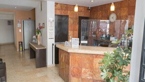 Un área de recepción con mostrador de piedra, un reloj y una planta.