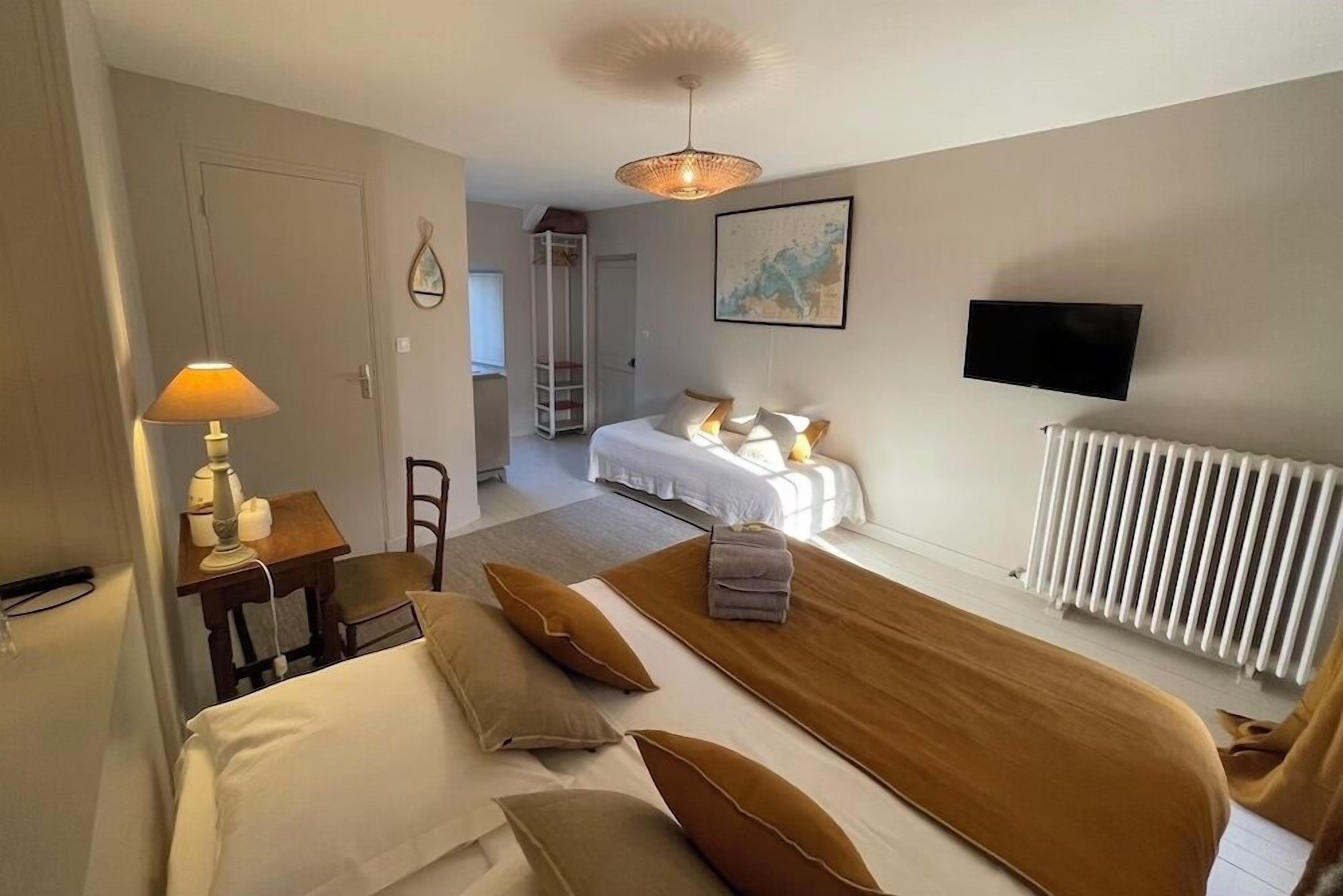 Une chambre d’hôtel comprenant un lit, un bureau avec une lampe, une chaise, un canapé, une télévision et un radiateur.
