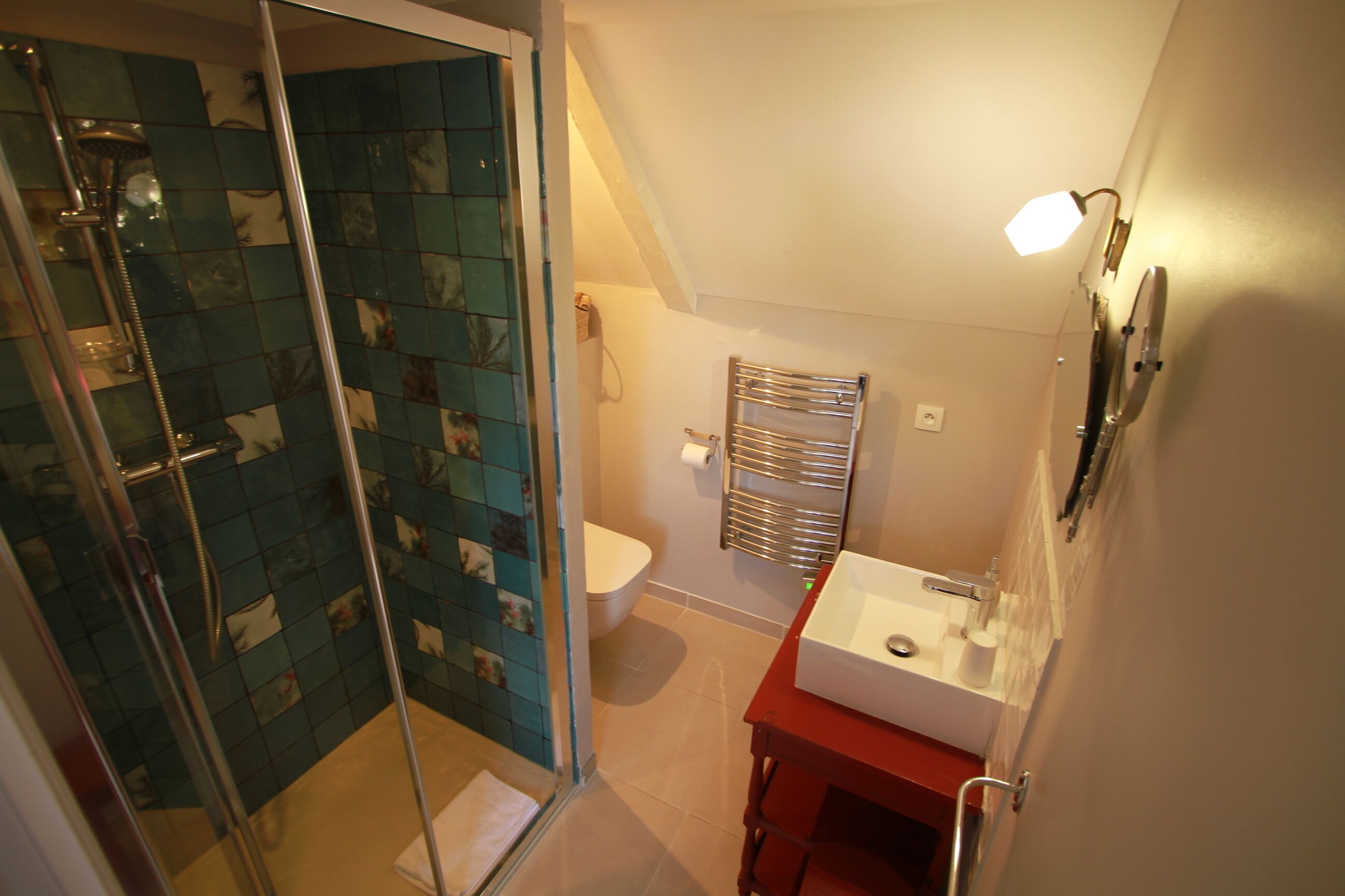 Une salle de bain avec une douche à parois de verre, un lavabo blanc et un meuble-lavabo rouge.